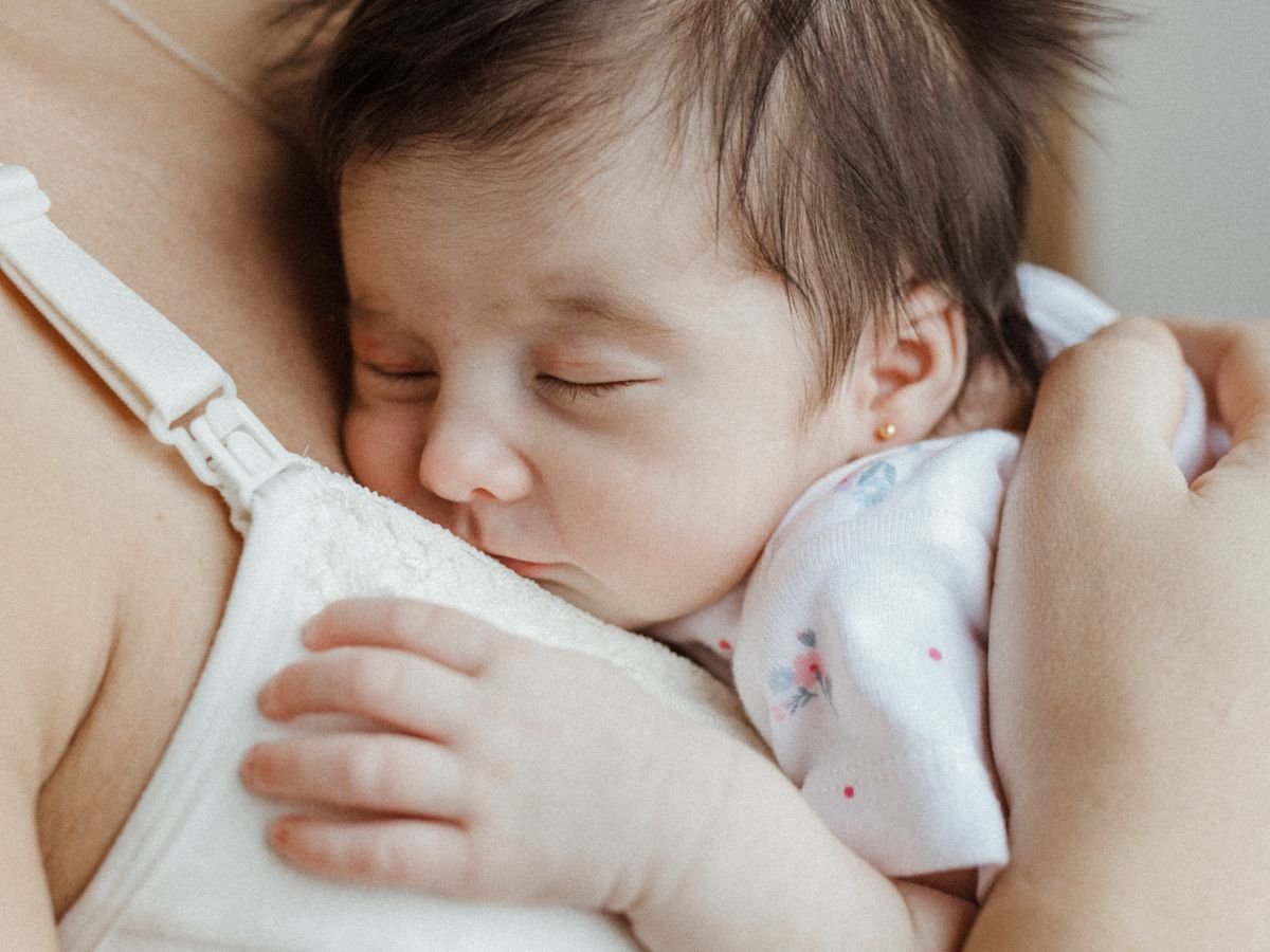 Newborn baby sleeping peacefully against a parent's chest